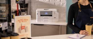 Woman in coffee shop holding a coffee cup with a printer in the background