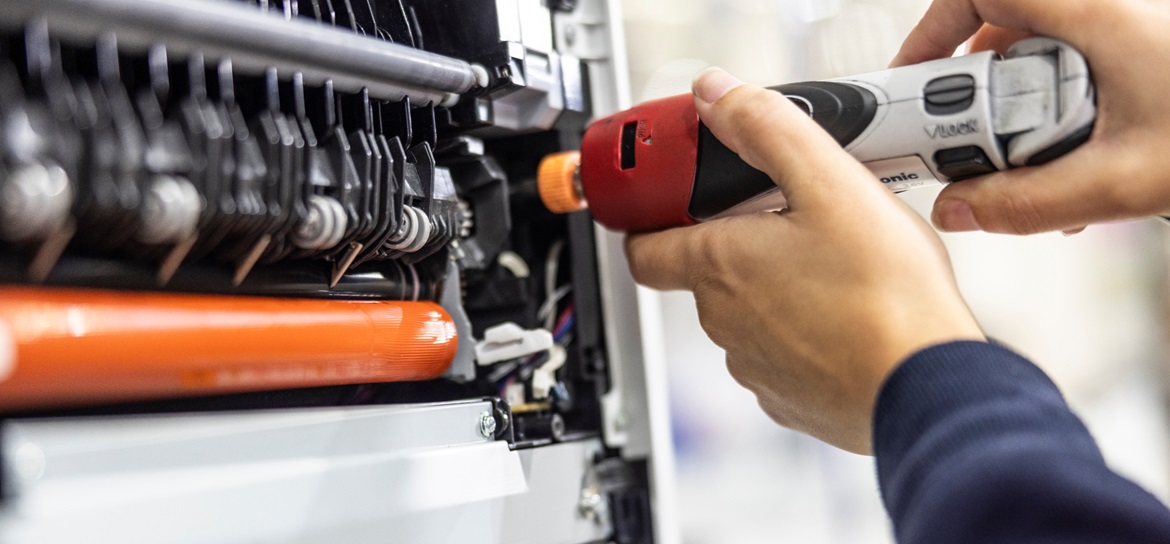 Hand holding a drill fixing a printer