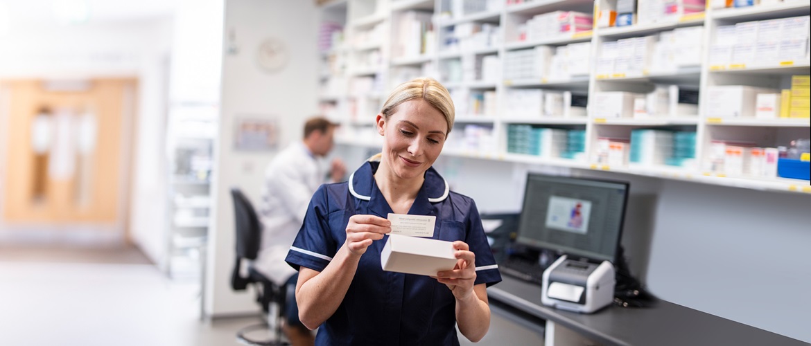 healthcare worker labelling a bottle of medicine