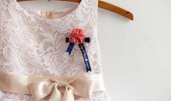 A bridesmaid's brooch pinned on their bridesmaid's dress, personalised with a Brother satin ribbon 