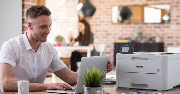 Man in white shirt on his laptop printing from his home printer