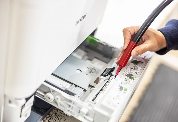 Hand holding a tool which is being used on an open Brother printer
