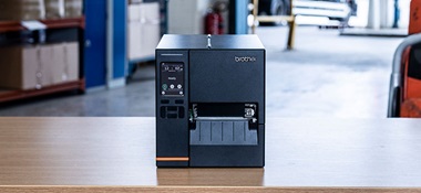 Black industrial label printer sat on table in warehouse