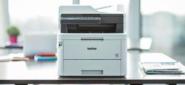 Brother MFC-L3770CDW Multifunktions-Farblaserdrucker auf einem Schreibtisch mit Pflanze im Hintergrund