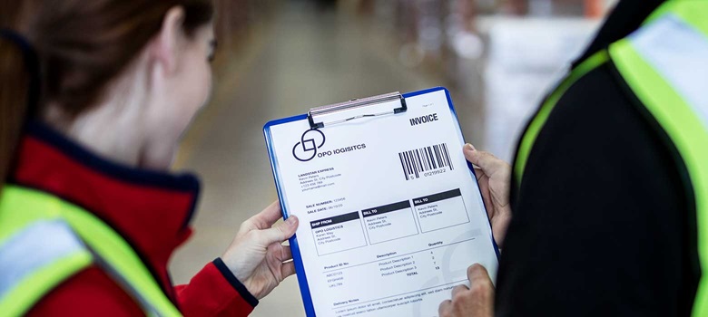 Man and woman wearing hi-vis holding clipboard with invoice in warehouse